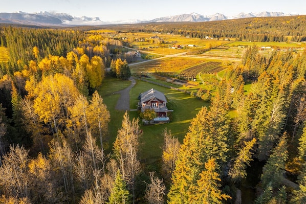 A lodge surrounded by forest with a view of mountains in the distance.