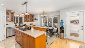 Una cocina moderna con armarios de madera, una isla grande y una zona de comedor con vistas a un paisaje nevado.