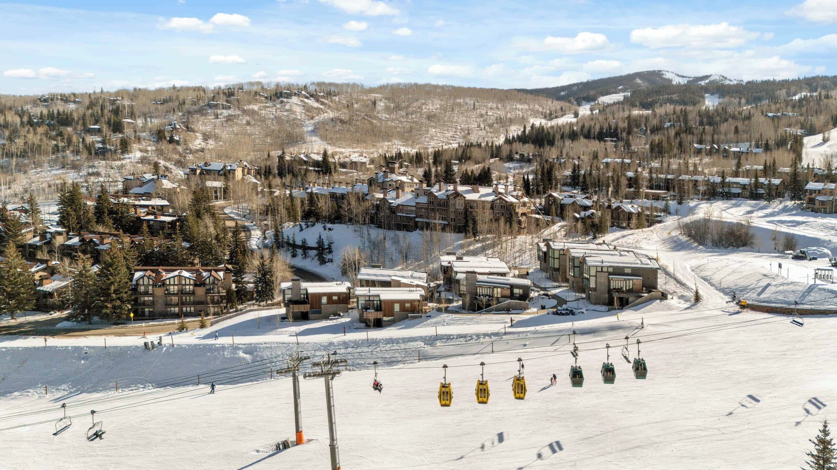 A ski resort with multiple buildings, a ski lift, and a snow-covered landscape.