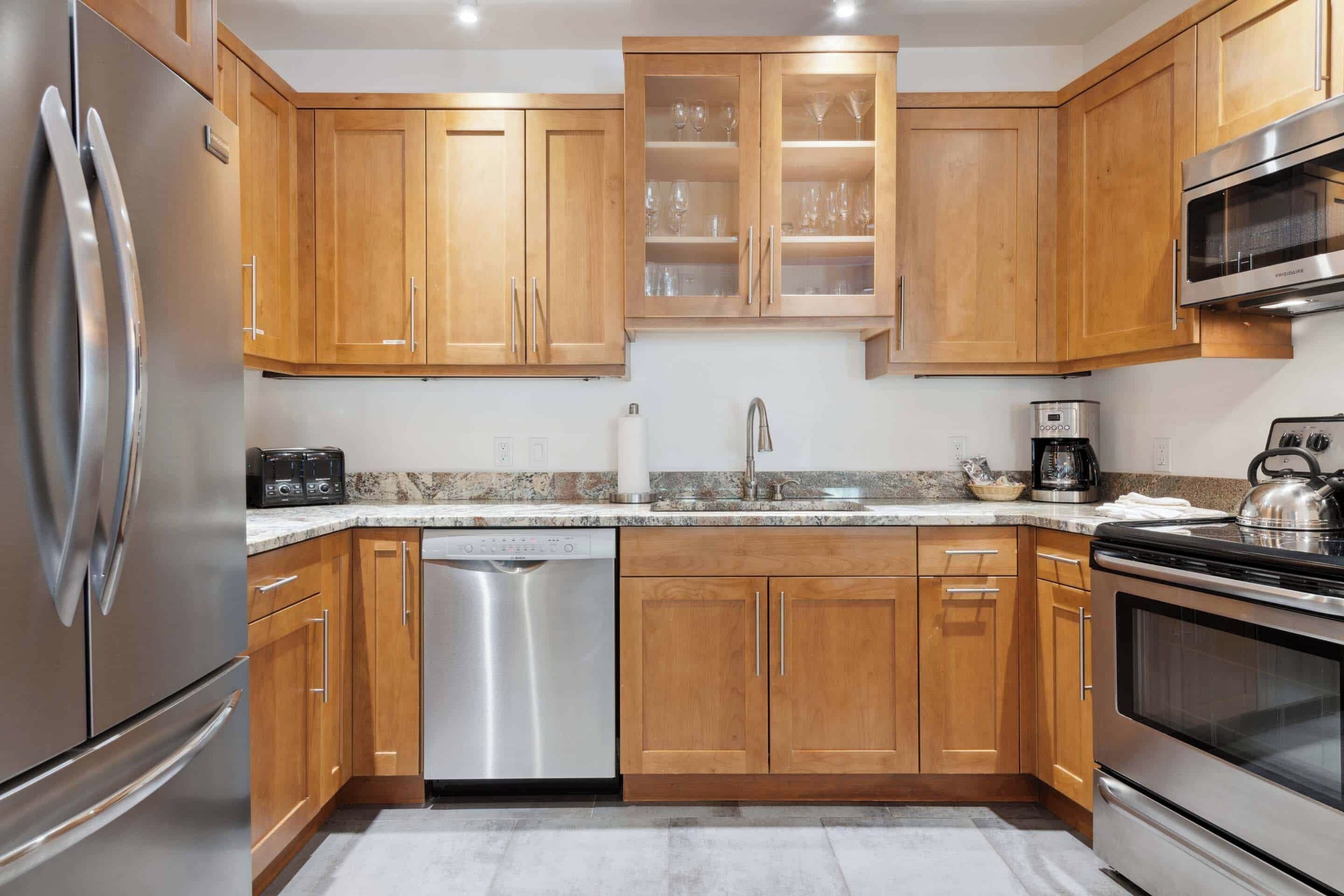 A modern kitchen with wooden cabinets, stainless steel appliances, and a granite countertop.