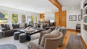 A spacious living room with a large sectional sofa, ottomans, a coffee table, and a bookshelf. - Woodrun Place 22 Three Bedroom Residence (Snowmass)