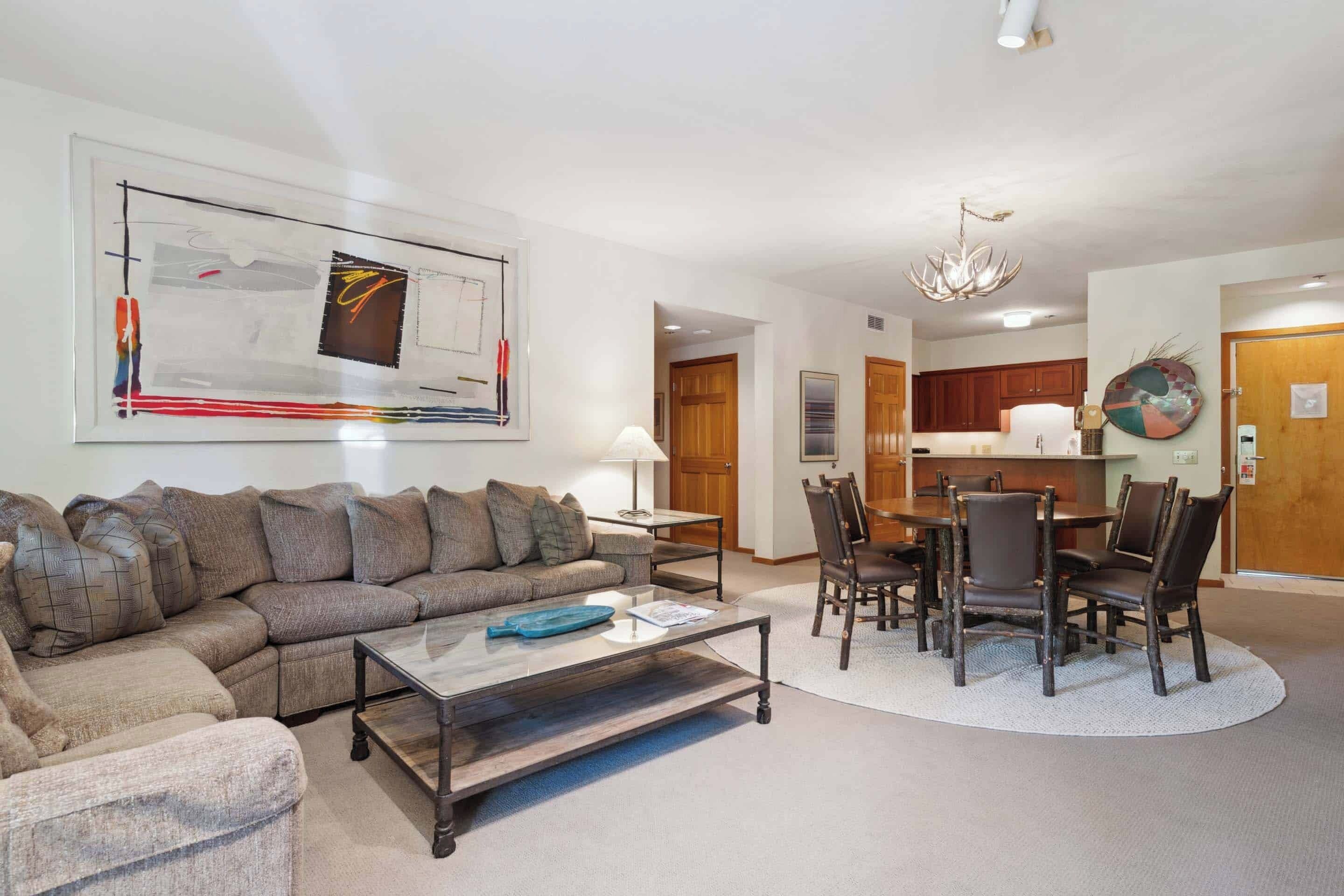 A living room with a sectional sofa, a coffee table, and a dining area with chairs and a table.