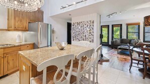 Una cocina amplia con encimeras de granito, armarios de madera y una isla grande con sillas.