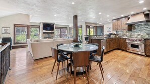 A spacious kitchen with a round dining table, wooden cabinets, and a large island.