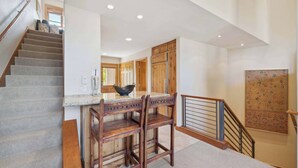 A staircase leading to a kitchen area with wooden cabinets and a dining table with chairs.