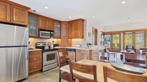 A spacious kitchen with wooden cabinets, stainless steel appliances, and a large island with seating. - Woodrun Place 50 Three Bedroom Residence (Snowmass)