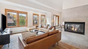 A spacious living room with a fireplace, large windows, and a modern fireplace screen.
