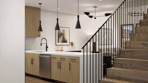 Une cuisine moderne avec des meubles en bois, un lave-vaisselle en acier inoxydable et des luminaires suspendus.