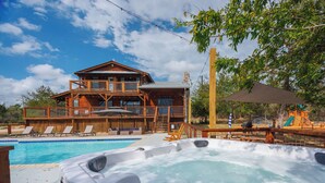 Uma casa de madeira de dois andares com piscina e banheira de hidromassagem.