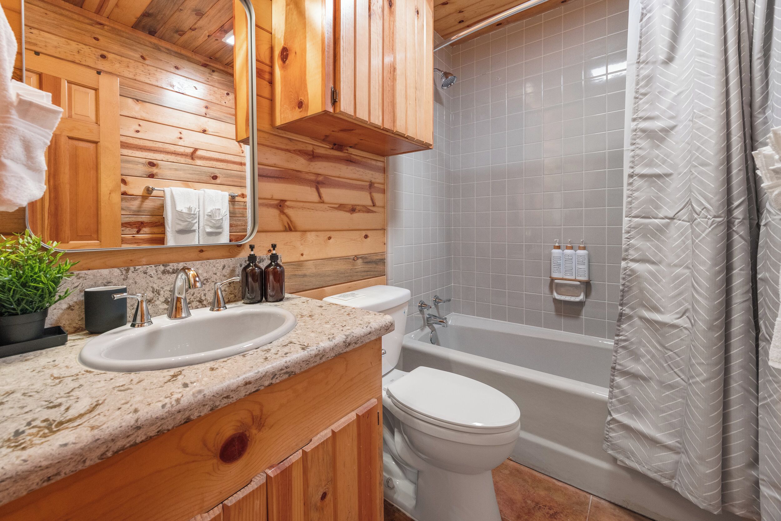 A wooden cabin bathroom with a sink, toilet, and bathtub.