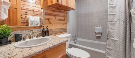 A wooden cabin bathroom with a sink, toilet, and bathtub.