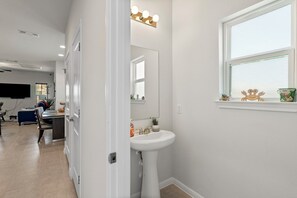 Bathroom features a pedestal sink, large mirror, and a vanity with a countertop.