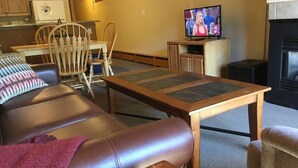 A living room with a leather sofa, a wooden coffee table, a television, and a fireplace.