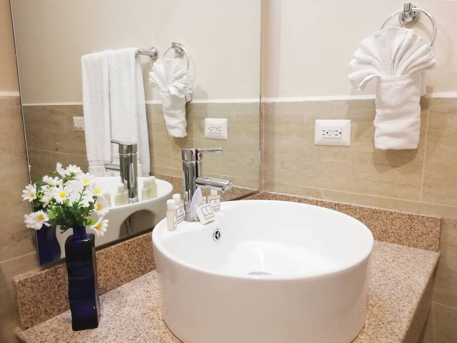 Een badkamer met een wit wastafelmeubel, chroombeslag, een spiegel en een handdoekrek.