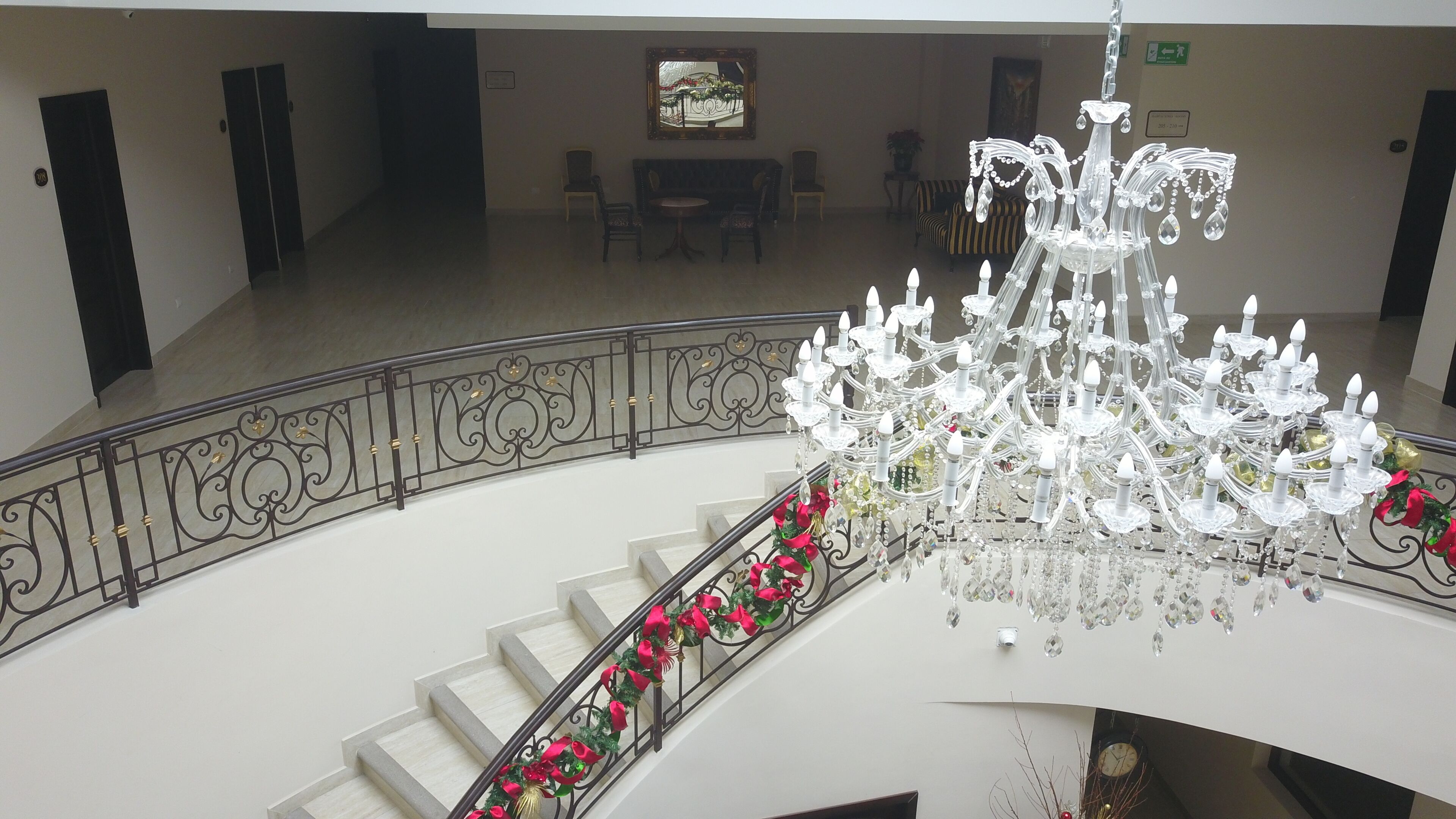 Un magnifique lustre trône dans un vaste hall, où un escalier orné de roses rouges attire le regard.