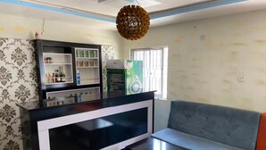 A living room with a black and white entertainment unit, a grey sofa, and a patterned wallpaper. - Clinclia Hotels (Ibadan)