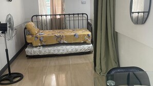 A compact room with a bed, a standing fan, a table with a glass top, and a mirror on the wall. - Beautiful Cozy Private Studio with WiFi in Charming Salisbury (Salisbury)