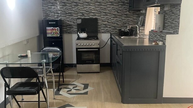 A compact kitchen with a gas stove, a refrigerator, and a dining area with chairs. - Beautiful Cozy Private Studio with WiFi in Charming Salisbury (Salisbury)