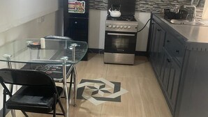 A compact kitchen with a stove, oven, and a refrigerator. There is a dining table with chairs and a decorative floor pattern. - Beautiful Cozy Private Studio with WiFi in Charming Salisbury (Salisbury)