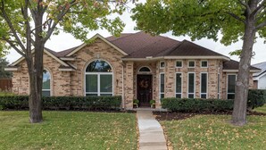 A brick house with a front entrance, a front yard, and a driveway. - Pool, Pool Table, Board Games + Butterfly Garden (McKinney)