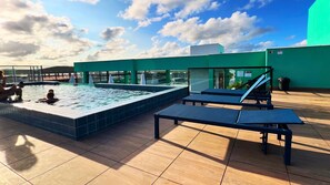 Un área de piscina en la azotea con sillas de descanso y una piscina.
