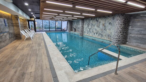 An indoor swimming pool with a tiled floor, a lifebuoy, and a stone wall. - Hotel Diego de Almagro La Serena Express (La Serena)