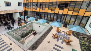 A modern building with a covered outdoor seating area, glass walls, and a stone wall. - Hotel Diego de Almagro La Serena Express (La Serena)