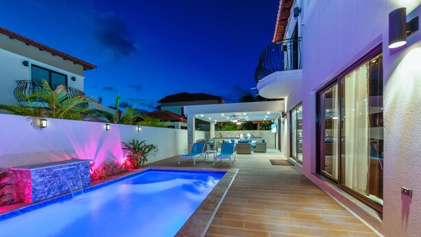 Ein modernes Haus mit Swimmingpool, Sitzgelegenheiten im Freien und einer Terrassenfläche.