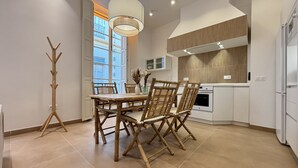 A modern kitchen with white cabinets, a wooden dining table with four chairs, and a hanging light fixture. - Zarzuela (Málaga)