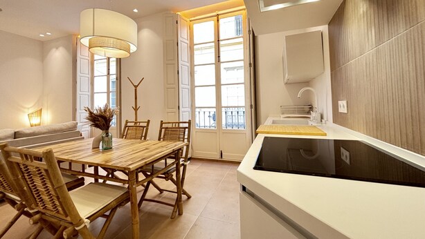 A modern kitchen with a large island, wooden dining table, and chairs. - Zarzuela (Málaga)