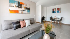 Una sala de estar moderna con un sofá gris, una mesa de centro y un comedor con mesa y sillas.