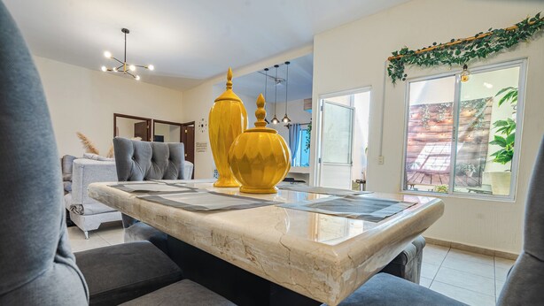 Uma sala de estar moderna com uma mesa de centro de mármore, sofás cinzentos e vasos decorativos amarelos.