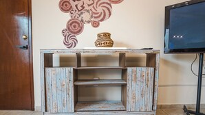 Uma estante rústica de madeira com um vaso decorativo, uma televisão e uma porta.