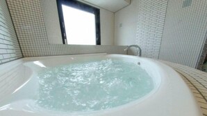 Uma banheira de hidromassagem em um quarto com paredes revestidas de azulejos e uma janela.