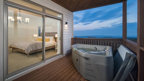 Un dormitorio con puerta de vidrio corredera, bañera de hidromasaje y vista a las montañas.