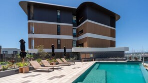 Um edifício moderno com piscina e espreguiçadeiras.
