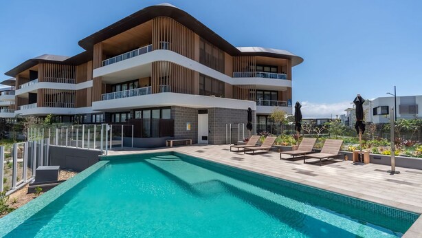 A modern multi-story hotel with a swimming pool and sun loungers. - Marina Getaway ~ Captivating 2-bedroom that accommodates up to 4 guests (Shell Cove)