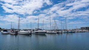 A marina with multiple boats docked, calm water, and a clear sky.
