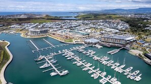 Marina com vários barcos atracados, um amplo complexo de edifícios e uma estrada sinuosa que conduz à marina.