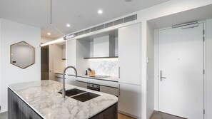 Cozinha moderna com bancada de mármore, eletrodomésticos de aço inoxidável e um espelho grande.