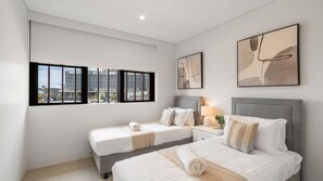 A hotel room with two beds, a nightstand, a lamp, and artwork on the walls. - Marina Getaway ~ Captivating 2-bedroom that accommodates up to 4 guests (Shell Cove)
