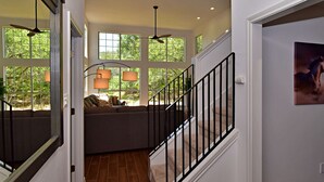 A staircase with a black railing leading to a landing with a sofa and lamps. - Dreamy Dripping Springs | Near Parks, Hiking & More! (Dripping Springs)