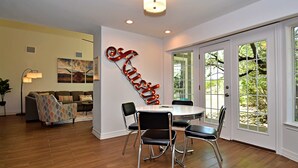 A dining area with a round table, four chairs, and a wall-mounted sign. - Dreamy Dripping Springs | Near Parks, Hiking & More! (Dripping Springs)