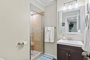 A bathroom with a glass shower enclosure, a sink with a mirror, and a towel hanging on the wall. - Starfish Shore -2BD/2BA Condo with BEAUTIFUL Ocean Views (Myrtle Beach)