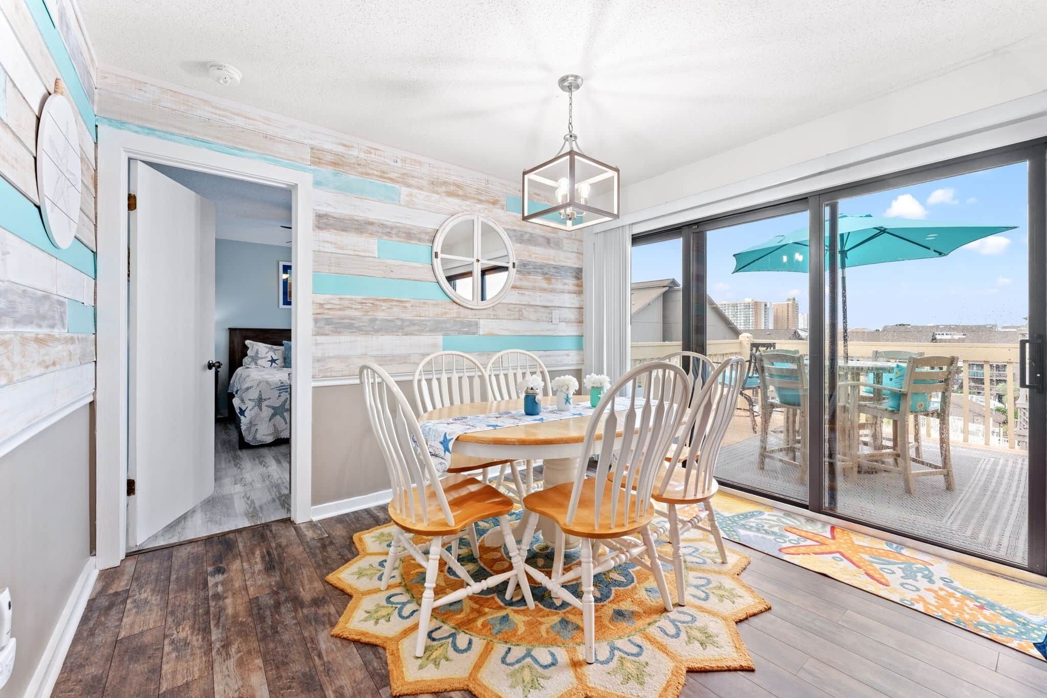 A dining area with a round table, white chairs, and a ceiling light fixture.