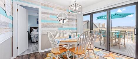 A dining area with a round table, white chairs, and a ceiling light fixture.
