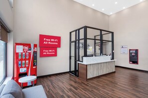 A reception area with a modern design, including a reception desk, a vending machine, and a sign indicating free Wi-Fi in all rooms. - Red Roof Inn PLUS+ Brooklyn - 3rd Ave (Brooklyn)