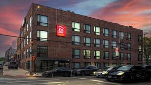 A multi-story brick building with a prominent Red Roof Plus sign, indicating a restaurant or cafe. - Red Roof Inn PLUS+ Brooklyn - 3rd Ave (Brooklyn)