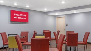 Sala de conferências com cadeiras vermelhas, uma mesa e um aviso indicando acesso gratuito à internet.
