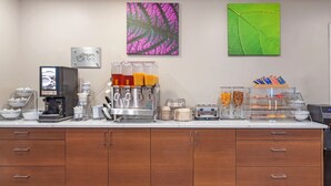 Ein Frühstücksbuffet mit Kaffeeautomaten, einer Kaffeepresse und verschiedenen Speisebehältern.